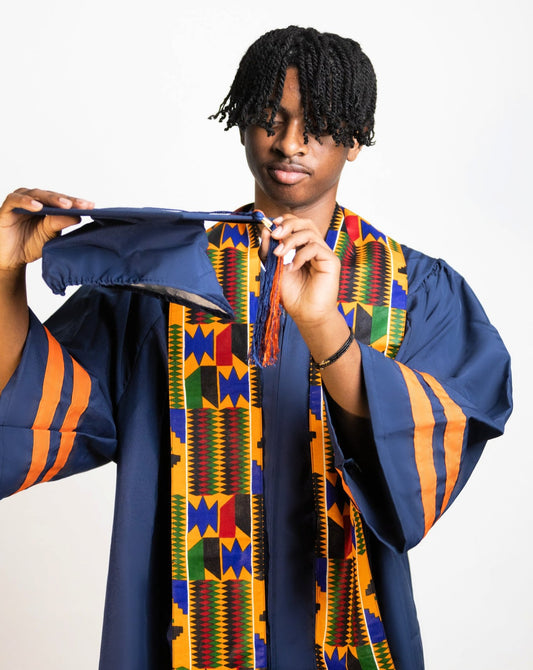 Student wearing graduation gown, holding graduation cap, wearing Kente Print sash